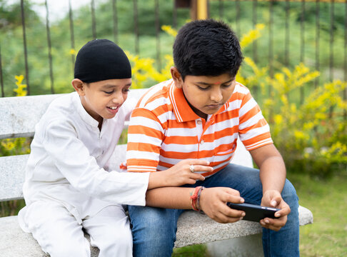 Mutiethnic Kids Playing Video Game On Mobile Phone At Park - Concept Of Technology, Smartphone Addiction, Friendship And Leisure Activities