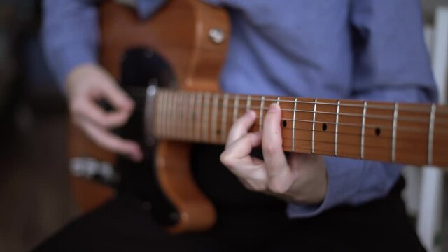 Guitar player hands playing telecaster with pick. A simple riff on electric guitar, course for beginner player online. Concept of music school and education