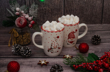 a couple of mugs with a fragrant drink with small marshmallows, an atmosphere of warmth and comfort, candles and fir branches