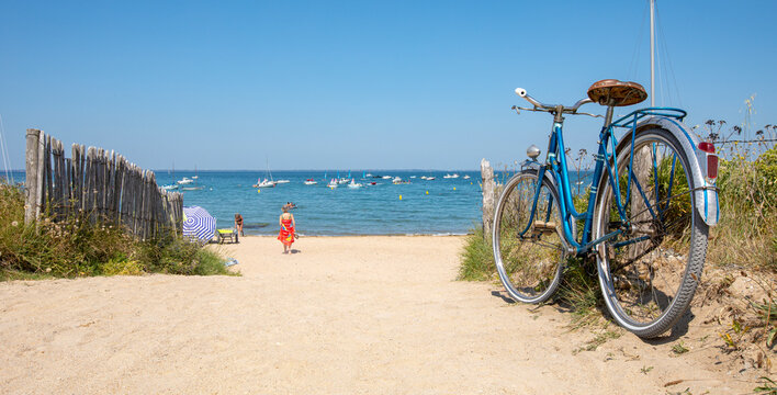 Vieux vélo bleu sur une plage de Bretagne en été.