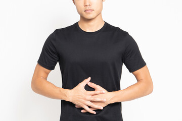 白い背景の前に立って、お腹に手を当てる黒いTシャツを着ている男性