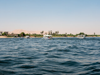 Luxor, Egypt - October 3, 2021: View of the Nile river and the coastline of Luxor. Boats transport people from one bank to the opposite bank along the Nile river.