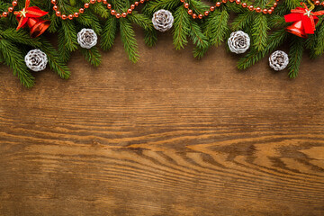 White cones, green fresh fir twigs, beads garland, red bells on dark brown wooden table background. Christmas decorations. Empty place for inspirational wishes text, quote or sayings. Top down view. © fotoduets