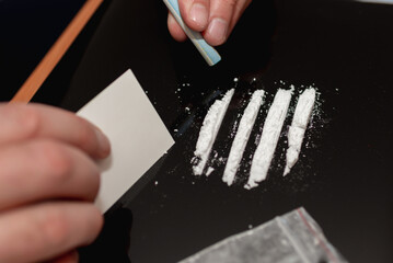 Drug addict. Drug abuse, man taking drugs, snorting lines of cocaine white powder, closeup, toned.