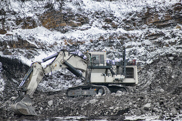 Big excavator in coal mine at cloudy day 