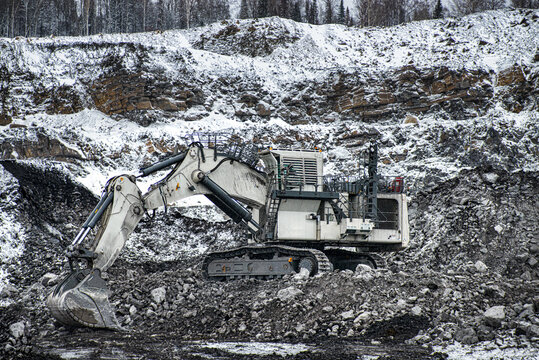 Big excavator in coal mine at cloudy day 