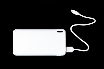 white power bank for charging smartphones and various digital devices on a black background close-up top view - 475270634