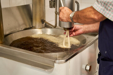 Cooking by pouring the churros dough into boiling oil on the stove, typical Spanish breakfast. 
