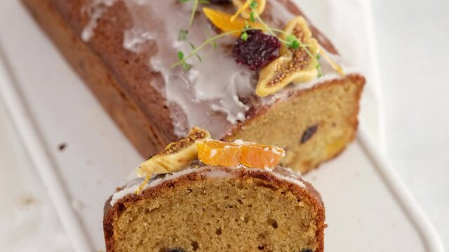 Top view. A sliced fruitcake soaked in rum is on the table. Christmas atmosphere with lanterns in the background. Christmas homemade muffin. Traditional cupcake with dried fruits. Camera movement.