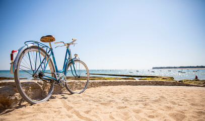 Vieux vélo bleu en bord de mer sur les plages du littoral français en Bretagne.