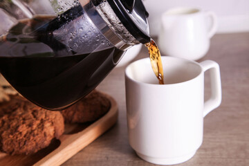 Hot coffee is poured into cup and oatmeal cookies