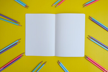 Blank notebook, a pencil, and space are on top of a yellow office desk table. Flat lay, top view education concept