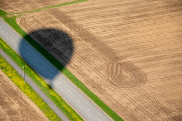 Hot air balloon flying over road and crops field