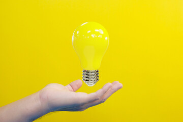 Hand holding idea light bulb and innovation thinking creative concept on success inspiration on yellow background