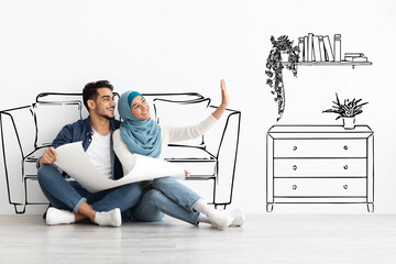 Happy arab couple sitting on floor in empty apartment