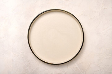 Empty white ceramic plate with black rim on a light textured background, flat lay, copy space