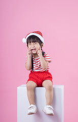 Cute of little boy wearing red santa hat  isolated on pink background.