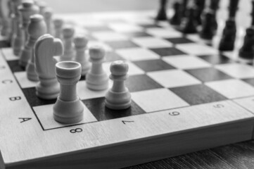 Chess' figures on game board. Set of chess pieces on the board. strategy games. Games for the development of intelligence. A part of game's board. Inexpensive set. Black-and-white photo.