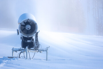 Snow making machine close up. Snow cannon in winter. Snow gun spraying artificial ice crystals. 