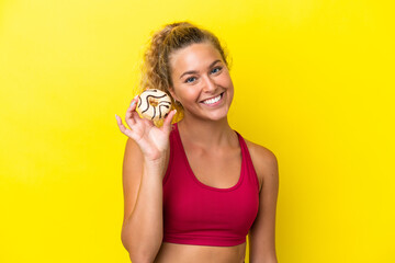 Girl with curly hair isolated on yellow background holding a donut and happy