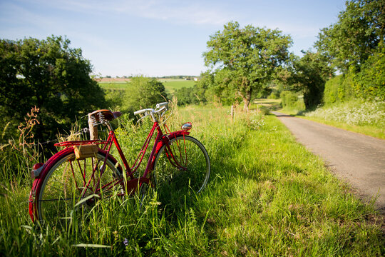 Vieux vélo rouge sur un chemin de campagne au printemps.