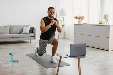 African Man Doing Forward Lunge Exercise Watching Online Workout Indoor