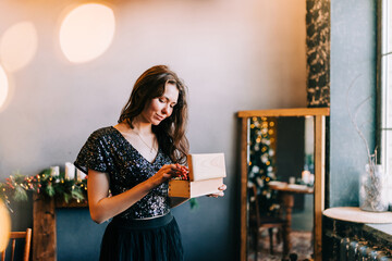 Portrait of a young woman during preparations for Christmas at home hold a box with xmas decorations