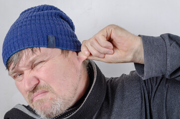 Portrait of a strange adult male pulling himself by the ear.