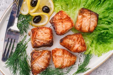 Grilled seafood. Grilled salmon slices with lettuce, lemon and olives on a plate.