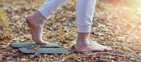 A woman walks with her bare feet on a board with sharp nails. Bare feet on sadhu board for yoga...