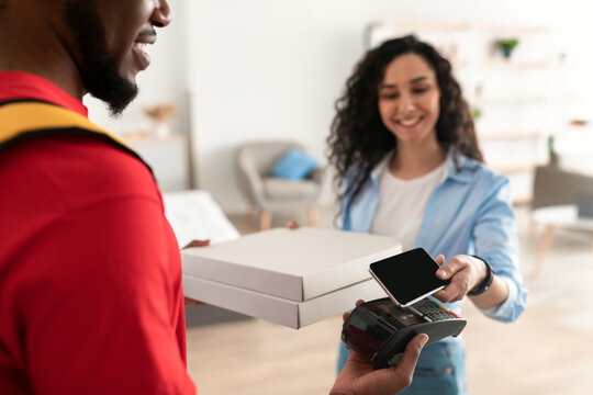 Black delivery man holding pizza box and pos terminal