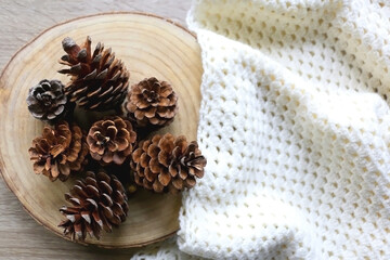 Wooden tray with pine cones and soft knitted blanket. Hygge at home. Flat lay.