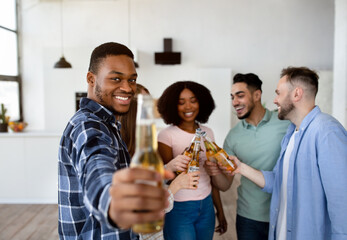 Cool black guy with bottle of beer and group of multiracial friends saying CHEERS, celebrating something, having party