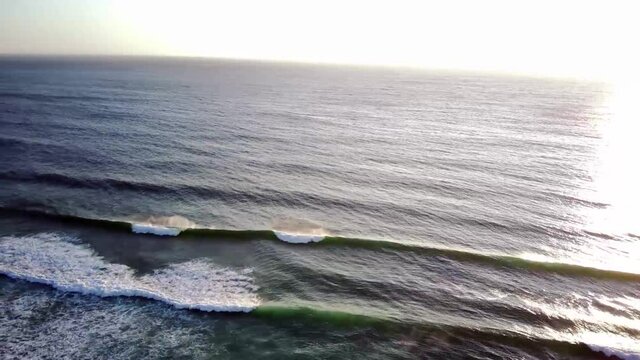 atardecer en el mar con olas plano de drone aereo lateral con paneo