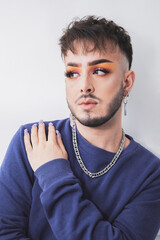 a young man with makeup posing on a white background with one hand on his chest.diversity concept.