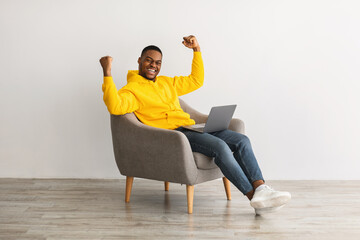 Guy With Laptop Gesturing Yes Sitting In Armchair, Gray Background