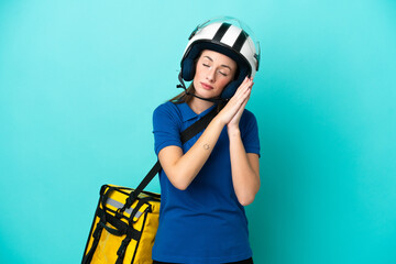 Young caucasian woman with thermal backpack isolated on white background making sleep gesture in dorable expression