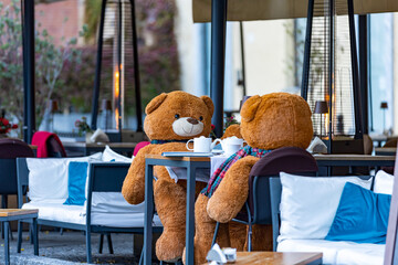 two teddy bears drinking tea sitting at a bar table in the Italian square