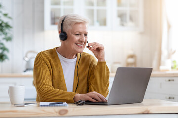 Happy old woman using laptop, having video conference