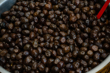 Marinated black olives with pits in a large barrel