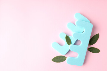 Nail separators and leaves on pink background