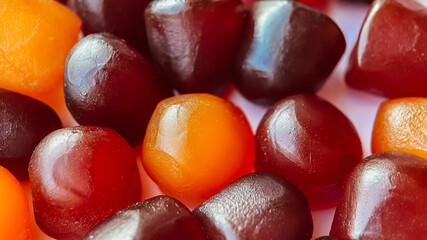 Selective focus.Close-up texture of red, orange and purple multivitamin gummies on white background
