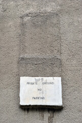 No Parking Sign Painted on Rough Textured Grey Cement Wall