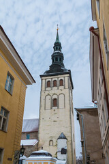 Low-angle view of apartment buildings and the tower of the Saint Nicholas Church in overcast winter day, Tallinn Old Town, Estonia
