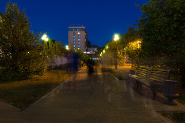 Fototapeta na wymiar Beautiful perspective view of the illuminated alley on the Square of the 400th Anniversary of Tyumen with people blurred in motion at dusk, Russia 