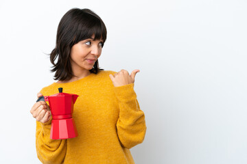 Young mixed race woman holding coffee pot isolated on white background pointing to the side to present a product