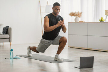 Black Guy Doing Forward Lunge Exercise At Laptop At Home - obrazy, fototapety, plakaty