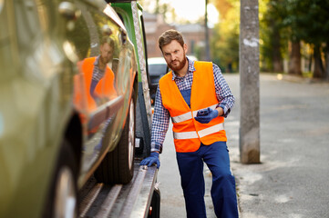 Tow truck worker checking car loading accuracy