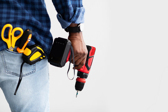 Men work concept. Black man holding screwdriver, with tools in pocket, white background with free space, back view