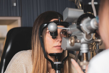 an optician measures a girl's corneal radii with a keratometer in a clinic.